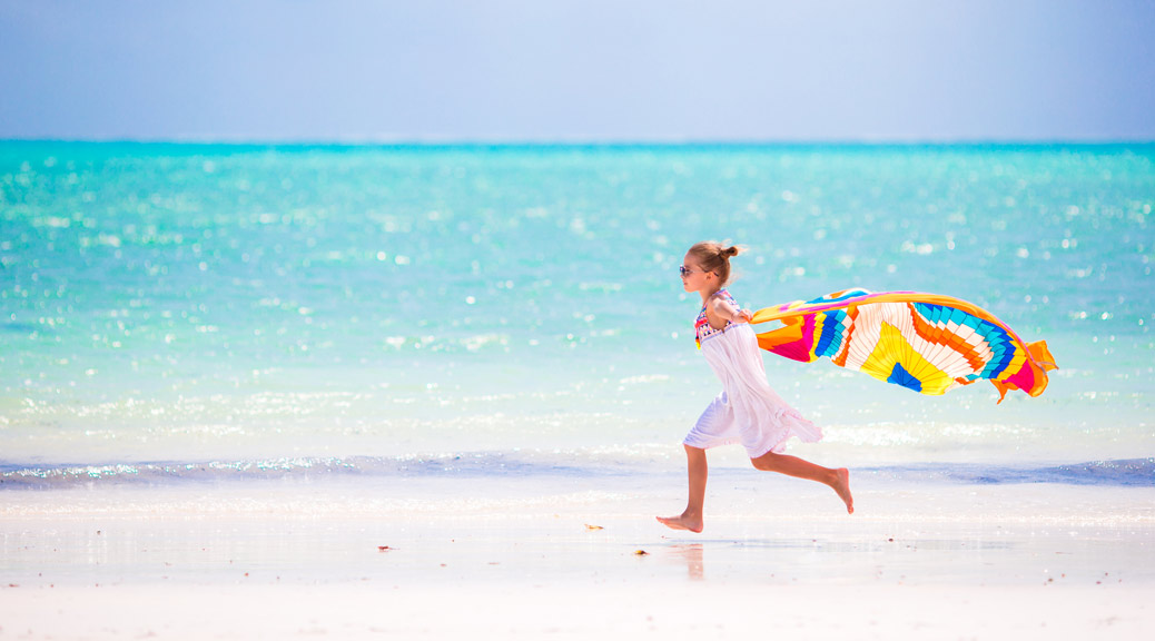 Little girl have fun on beach with towel during vacation